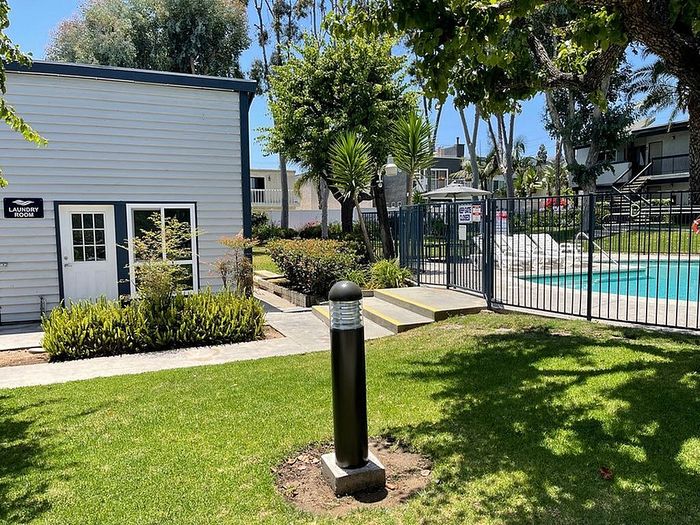 On-site laundry room building exterior beside green lawn and fenced pool at Delaware Pines.