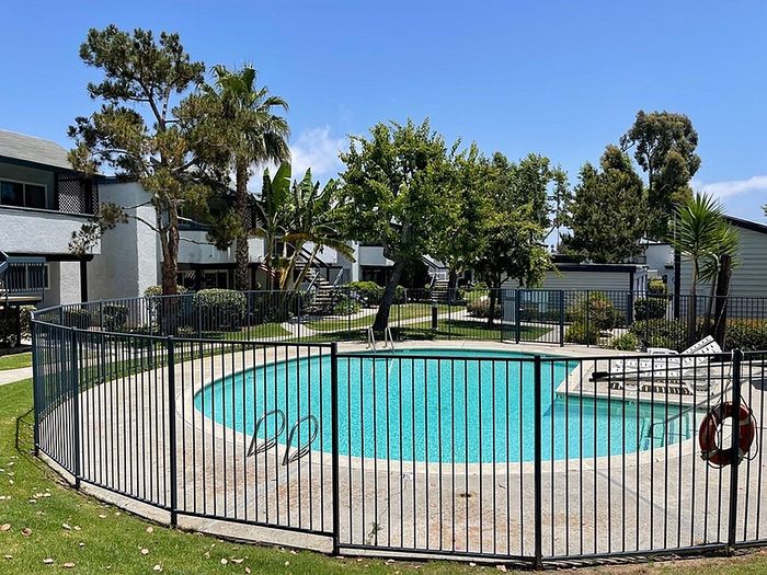 Circular outdoor swimming pool enclosed by metal fence with lounge chairs at Delaware Pines.