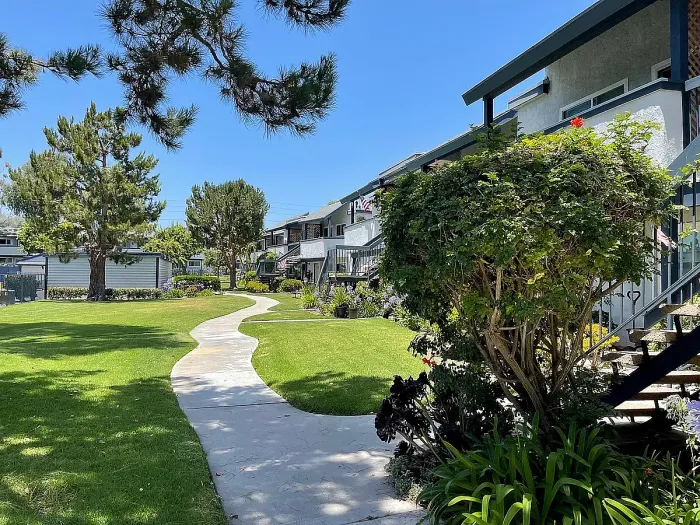 Manicured lawn, shade trees, and concrete path outside Delaware Pines apartment residences.