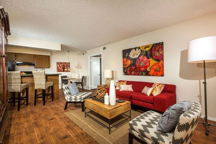 living room with vinyl wood like flooring and red sofa and 2 arm chairs at Metro on Main