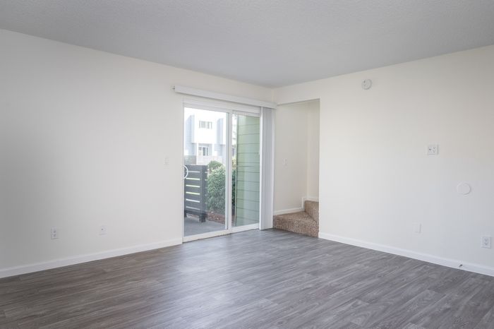 Living space with updated, wood-inspired flooring leading out to a private patio