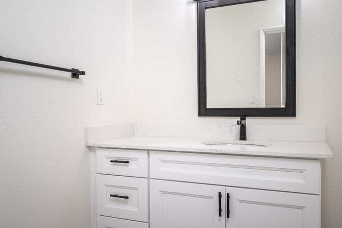 Updated bathroom with white shaker cabinets and white hard-surface countertop