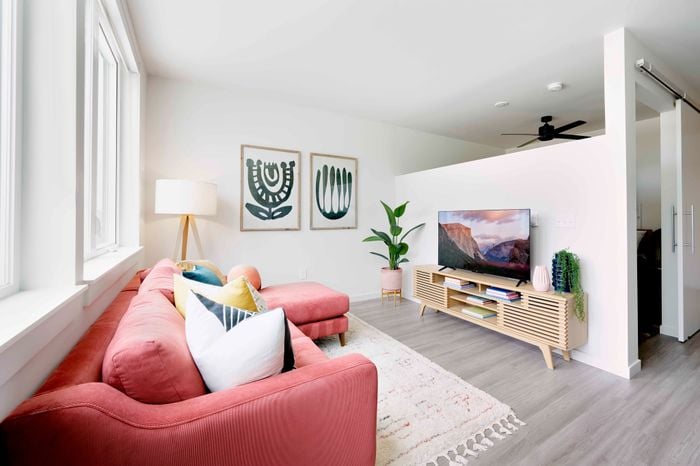 living room with red sofa, vinyl wood like flooring and tv console at novus woodstock apartments