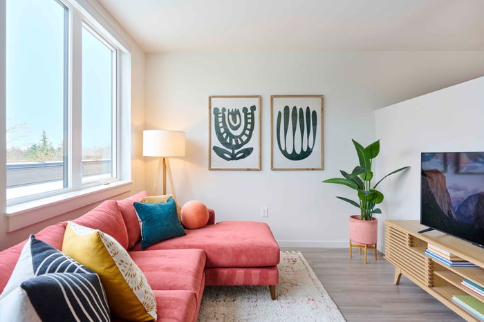Portland Apartments- Novus- Living Room with Spacious Windows, Wood-Style Flooring, and Pink Couch