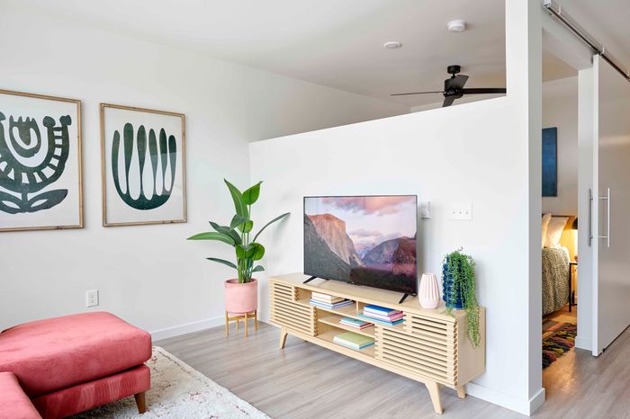 living room with red sofa, vinyl wood like flooring and tv console at novus woodstock apartments