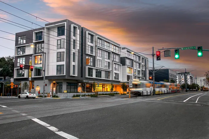 4 story aniva apartment building with the sun setting in the backgroun