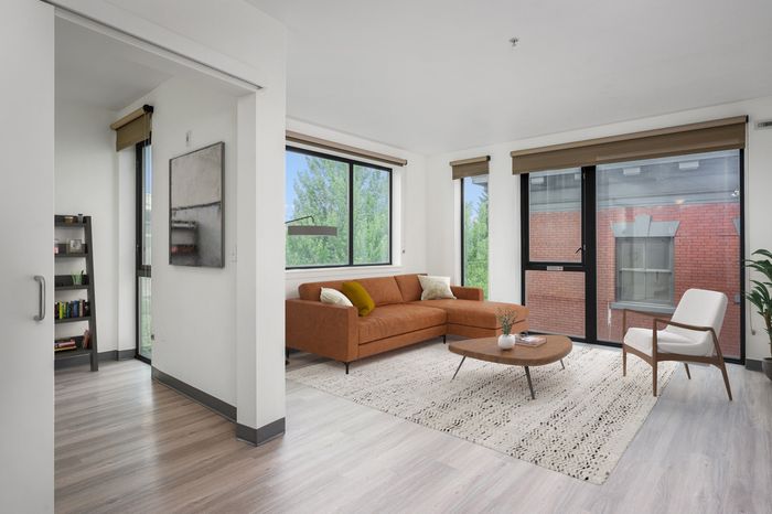 Virtually staged living room and bedroom with wood-style flooring and floor to ceiling windows allowing natural light