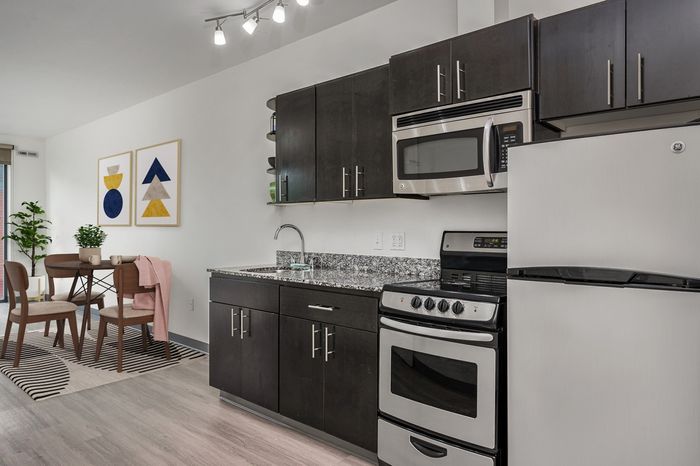 Virtually staged kitchen with stainless steel appliances, espresso cabinets and wood-style flooring