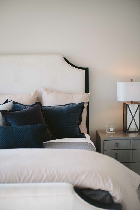 bed with white comforter and blue pillows