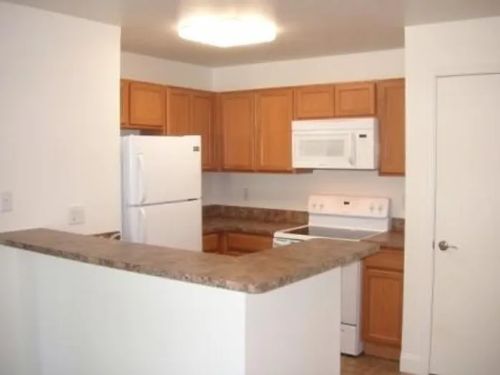 kitchen with breakfast bar and white appliances at brooktree apartments