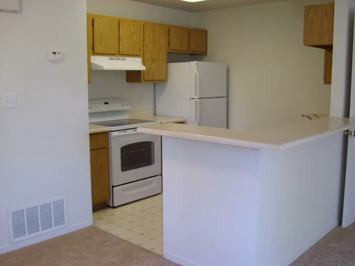 kitchen with vinyl flooring breakfast bar and white appliances at brooktree apartments