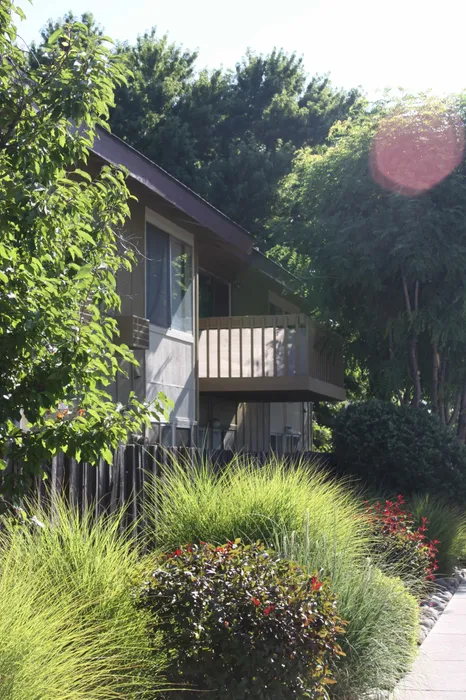 view of two story apartment building with lush landscaping at plumas garden apartments