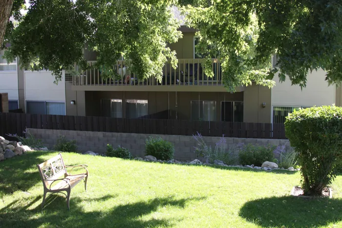grassy area with bench and patios in the background at plumas garden apartments