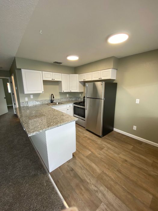 kitchen with black appliances bar area and wood inspired flooring at the creek at south carson