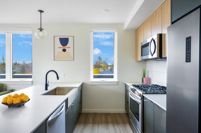 Apartments for Rent in Portland, OR - Novus - Kitchen with a Granite-Style Island, Stainless-Steel Appliances, and Wooden Cabinets