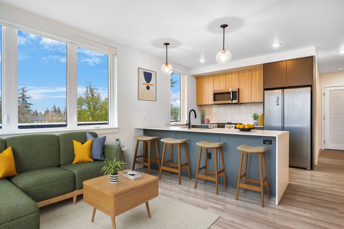 Apartments Portland, OR -Novus - Living Room with Spacious Windows, Wood-Style Flooring, and Outdoor Community View
