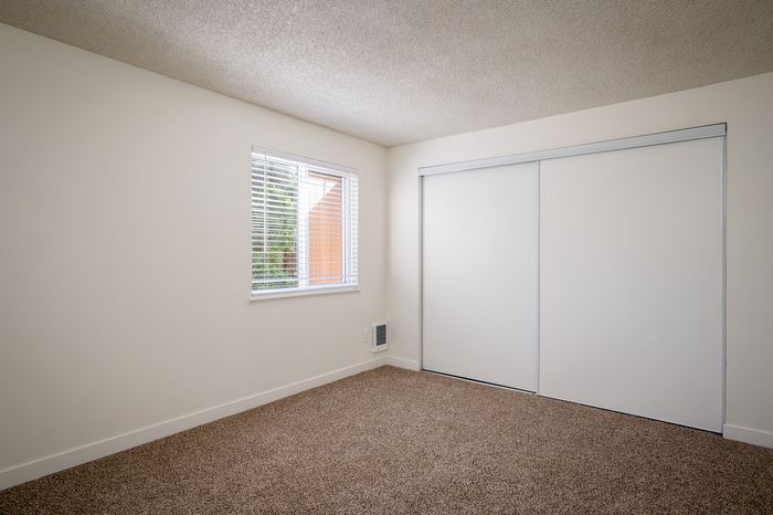 bedroom with brown carpet and large closet with sliding doors