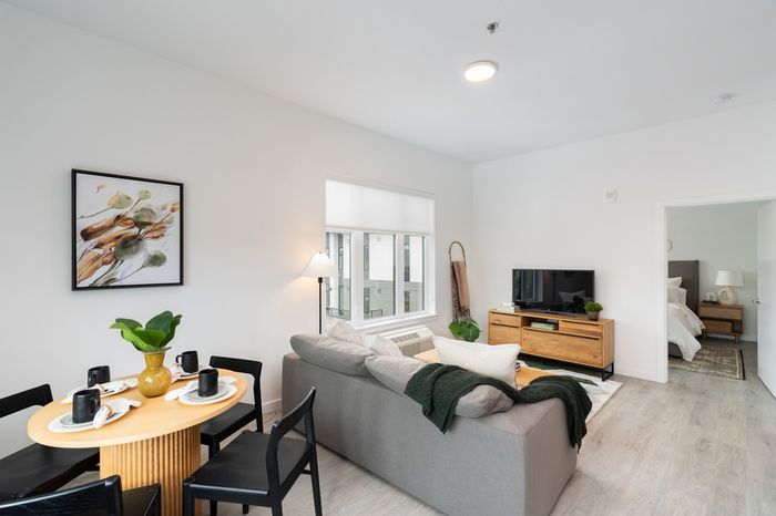 open floor plan with grey sofa and circular dining table behind