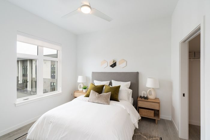 bedroom with large window and bed with side table and decorative pillows