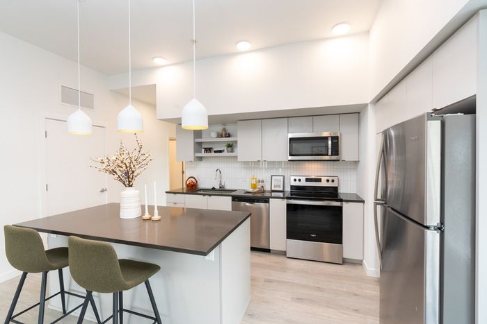 kitchen with stainless steel appliances and faux hardwood floors and quartz counters