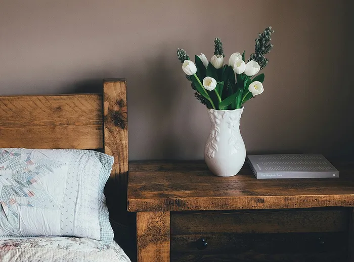 side table with flower vase with tulips next to bed