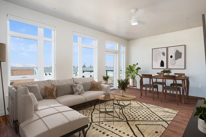 Spacious living room with large windows and abundant natural light, a dining space, and luxury vinyl plank flooring