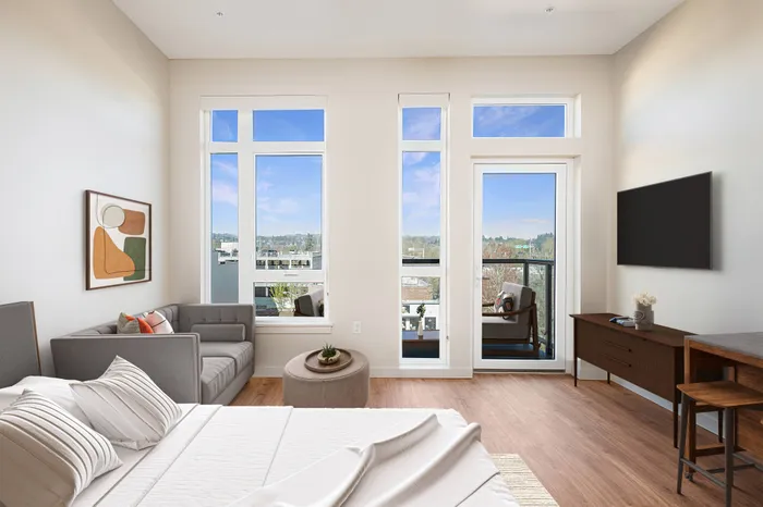 Studio apartment with virtually staged lounge area, queen sized bed and rolling bar seating area. Large windows allowing natural light with a patio and amazing view complete with patio furniture