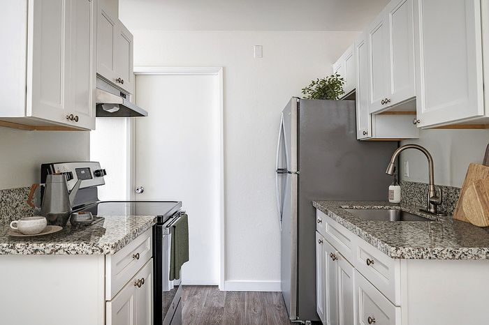 virtually staged kitchen with faux hardwood flooring and white cabinets and stainless steel appliances and decorative accessories