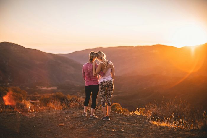 two women looking at the sunset at the top of a hill