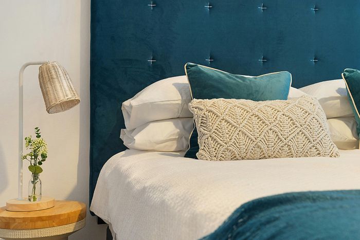 teal bed headrest and comforter along with round table with a lamp