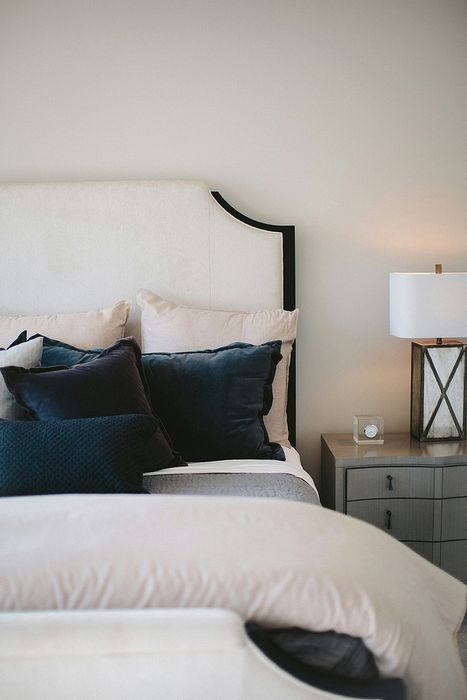 bed with blue accent pillows and grey side table with lamp