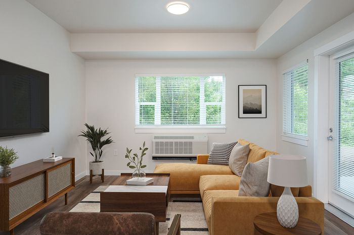Albany, OR, Apartments for Rent - Creekside Meadows - Living Area with White Walls, Wood-Look Flooring, a Sectional Sofa and Lamp, Coffee Table, TV Console, and Seating Area Set Off with an Area Rug.