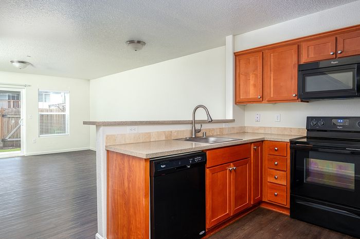 kitchen with wood cabinets and all black appliances and living area