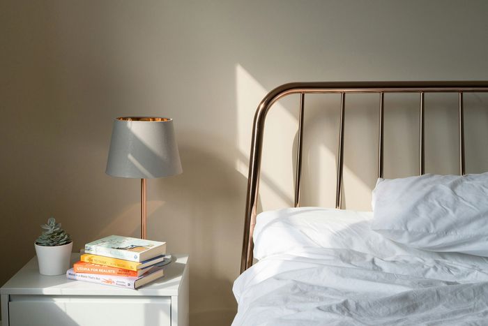 bed with metal headboard and side table with lamp and books
