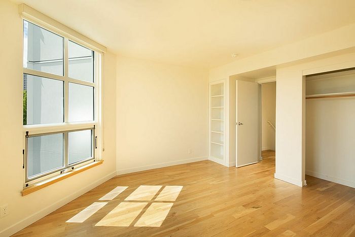 bedroom with hardwood flooring and large windows and closet with sliding doors