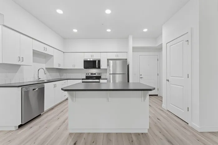 Kitchen with wood-style flooring, stainless steel appliances and kitchen island.
