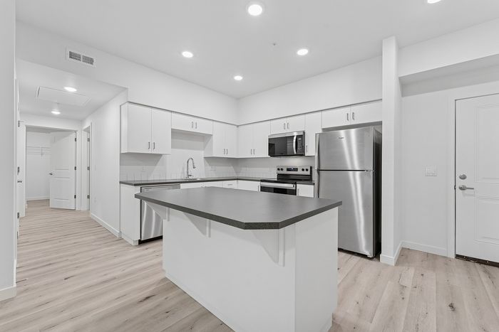 Kitchen with wood-style flooring, stainless steel appliances and kitchen island.