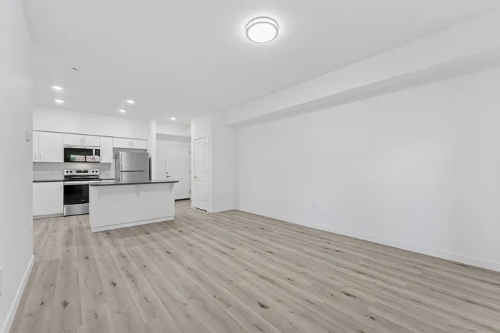living area and kitchen with wood-style flooring, stainless steel appliances and kitchen island.