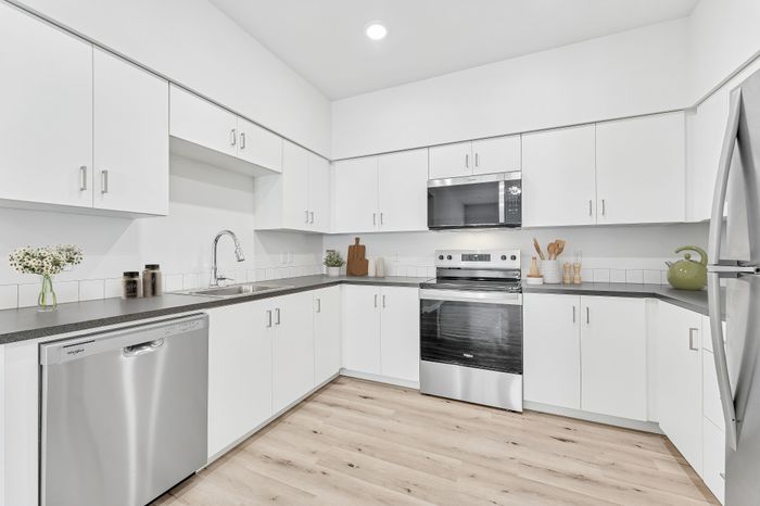 virtually staged kitchen with stainless steel appliances, white cabinets and grey countertops at Spring Meadow, in Newberg, OR
