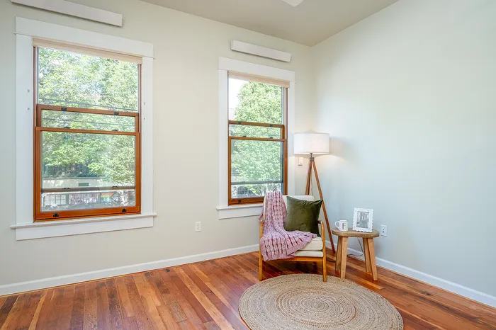 Living room with original hardwood flooring and wood-trimmed windows at Fairmount apartments in Portland, OR