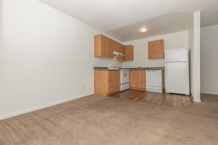 carpeted dining area and kitchen with white appliances and wood like flooring