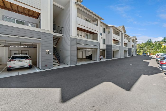 Pet-Friendly Apartments in Tigard, OR - Pacific Ridge Apartments - An Integrated Garage Parking Below the Apartments, with Parked Cars and View of the Apartment Staircase and Balconies.