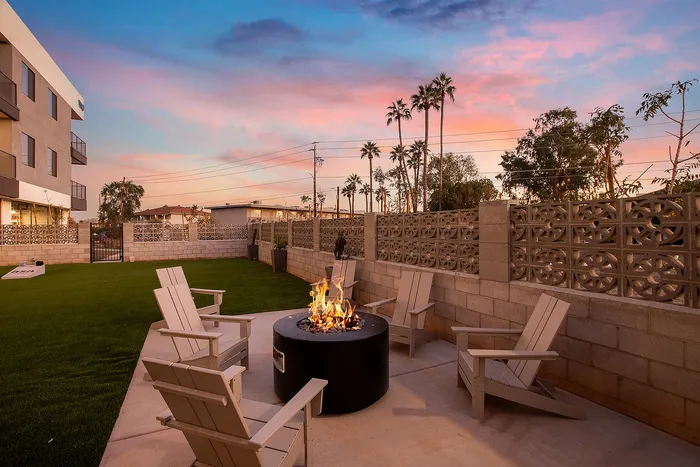 Midtown Phoenix, AZ, Apartments Near Indian School Steele Park - Asa Midtown - Fire Pit In The Outer Courtyard With Lounge Chairs, Turf Lawn, And Palm Trees Under Sunset Sky.