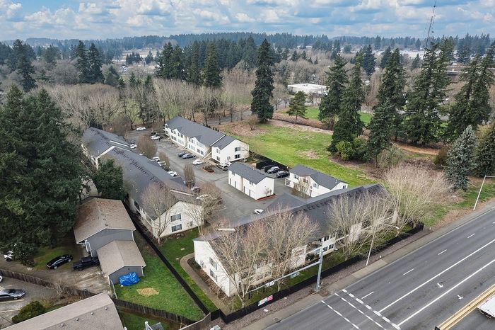 Aerial drone shot of property and surrounding area showing woodland with lots of trees alongside the road and natural horizon