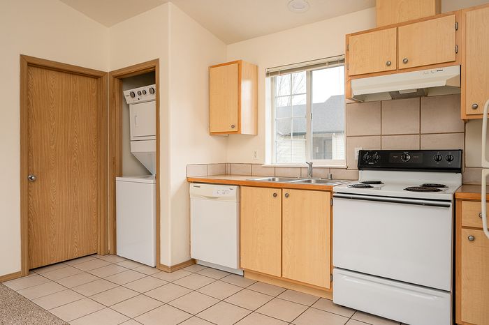 Kitchen showing in-unit laundry, dishwasher, and oven.