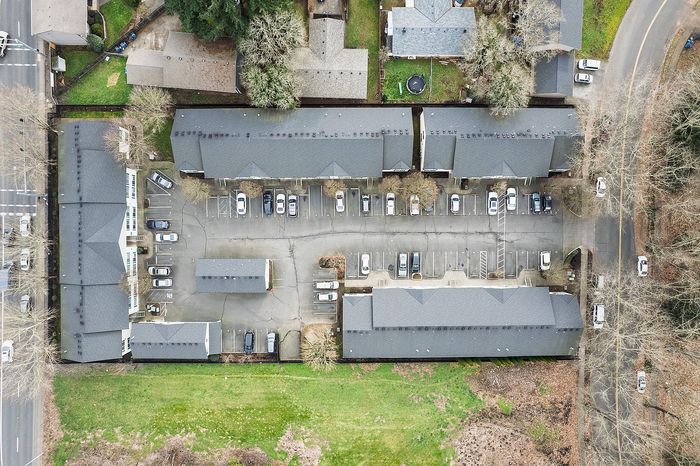 birds-eye-view showing entire property of apartments and parking and surrounding terrain.