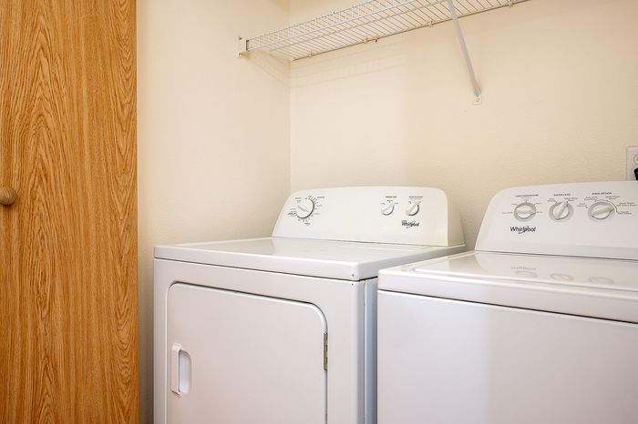 Laundry area with washer and drier and rack above.