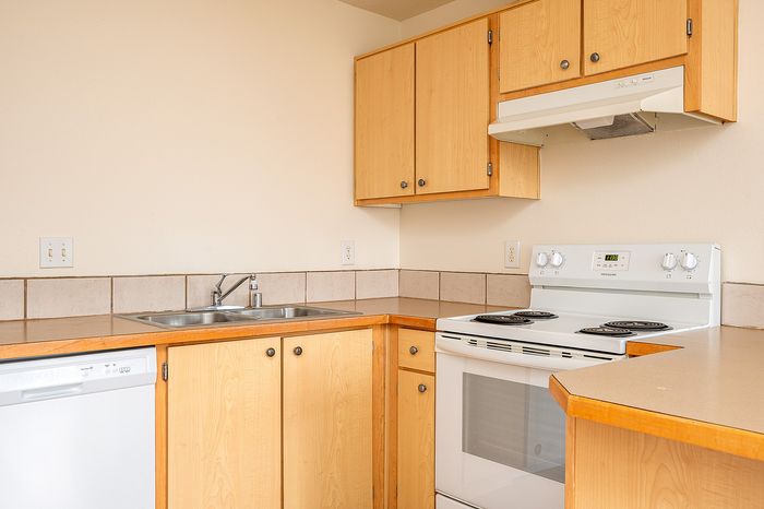 Kitchen with sink, oven, stove, dishwasher, countertops, and ventilation.