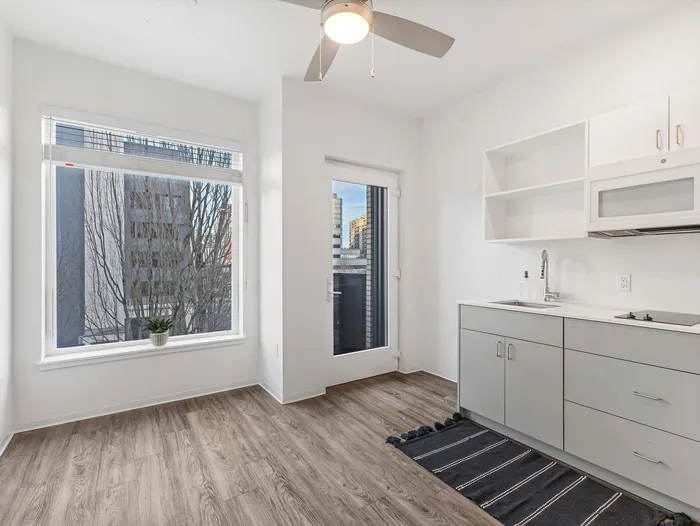 Studio kitchen with white cabinetry and large windows at Koz on 4th.