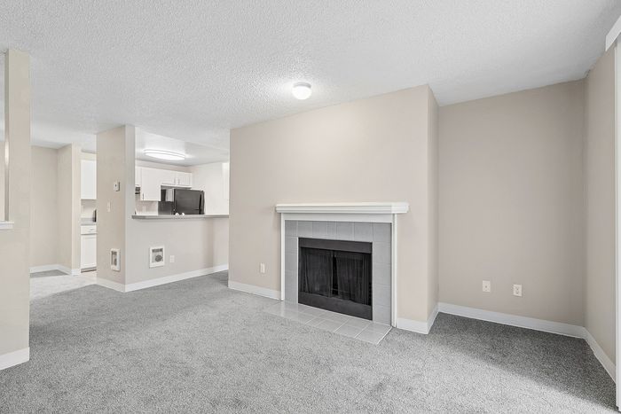 angle 2 of living room at B1 renovated floorplan at Timber Flats showing fireplace and view into kitchen
